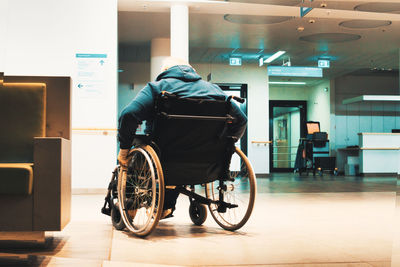 Rear view of man sitting in bus against building