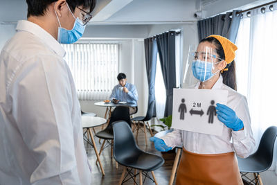 Rear view of female doctor examining patient in hospital