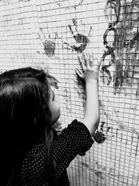 Side view of girl hand printing on wall