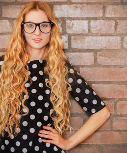 Portrait of woman wearing sunglasses against wall