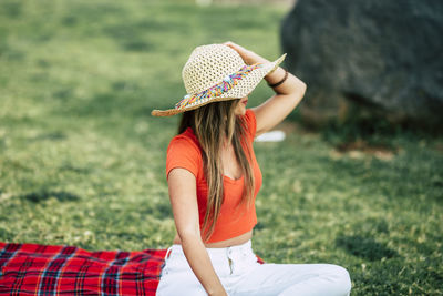 Midsection of woman wearing hat sitting on field