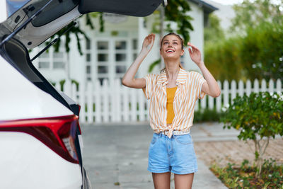 Full length of young woman standing against trees