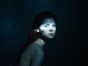 Portrait of a beautiful young woman over black background