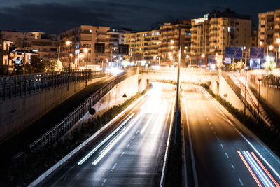 High angle view of light trails on city street amidst buildings at night