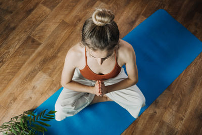 Rear view of woman sitting on wooden floor