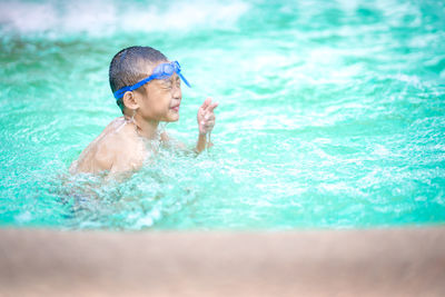 Full length of shirtless man swimming in pool