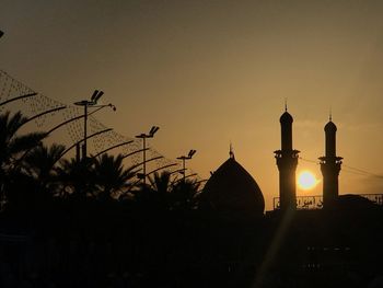 Silhouette of temple against building during sunset