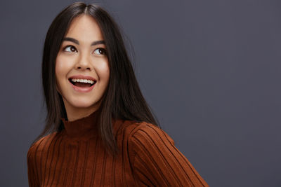 Portrait of young woman against black background