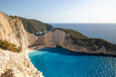 A beautiful view of a deserted beach with a sunken pirate ship washed ashore on a sunny summer day