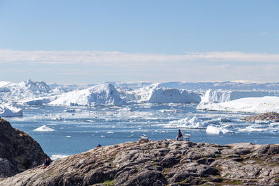 Scenic view of sea by snowcapped mountain against sky