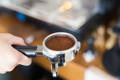 Cropped hand of woman holding ground coffee in filter