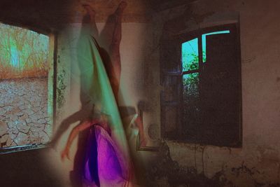 Rear view of woman standing against window in building