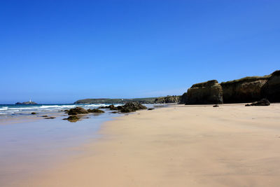 Scenic view of beach against clear blue sky