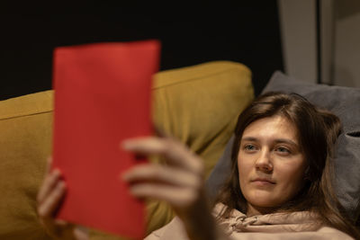 Woman reading book while lying at home