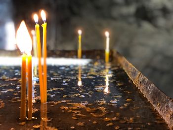 Close-up of lit candles in temple against building