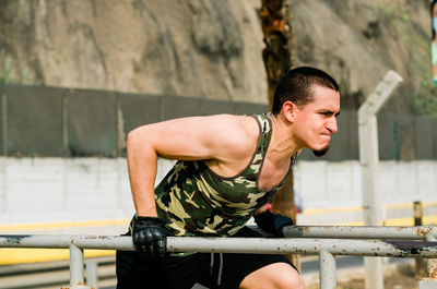 Young man looking down while railing against blurred background