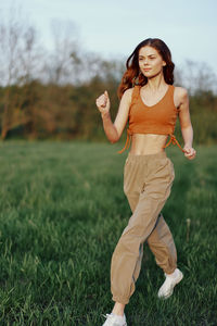 Full length of young woman exercising on field