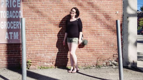 Full length of woman standing against brick wall