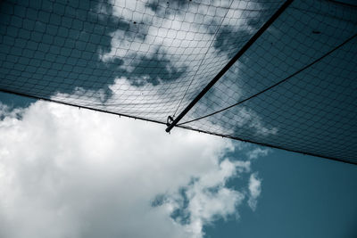 Low angle view of netting against cloudy sky