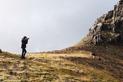 Man photographing through camera on field against sky