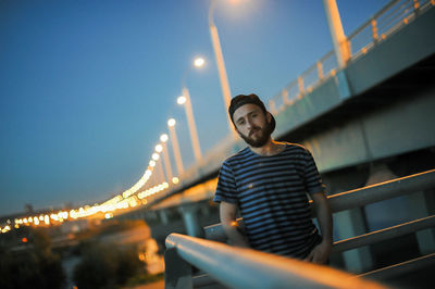 Young man standing on bridge at night