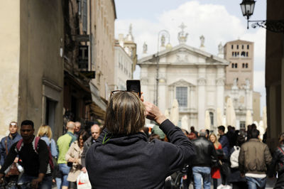 Rear view of people standing on street against buildings