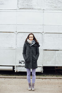 Portrait of young woman standing on road against vehicle