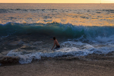 Wave over a person during sunset