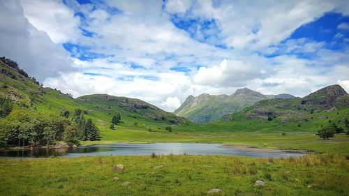 Scenic view of mountains and lake against cloudy sky