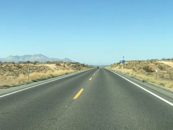 Road by landscape against clear blue sky