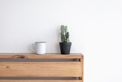 Potted plant on table against white wall