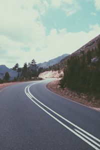 Road by mountains against sky