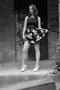 Portrait of young woman standing against building