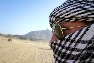 Close-up of man in desert against clear sky