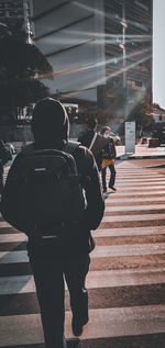 Rear view of man standing on footpath by building