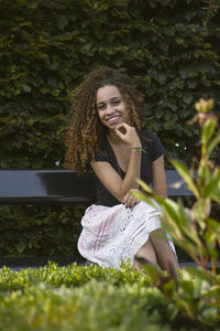 Portrait of young woman smiling while sitting on bench