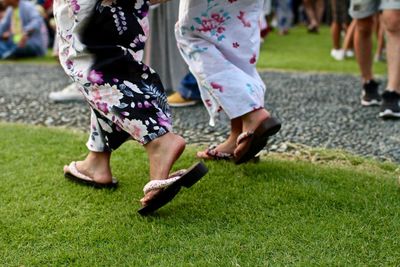 Low section of japanese women walking on grassy field