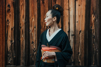 Woman looking away while standing on wood