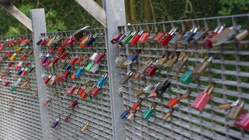 Multi colored padlocks hanging on metal fence