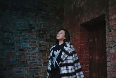 Woman standing against brick wall