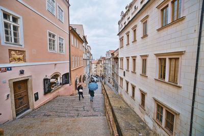 Rear view of people walking on street amidst buildings in city