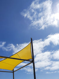 Low angle view of yellow flag against blue sky