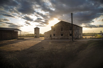 Old building on field against sky during sunset