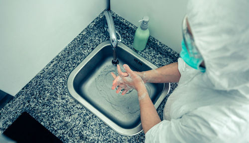 High angle view of doctor washing hands in bathroom sink