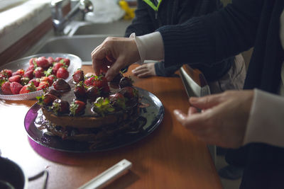 Midsection of man preparing food in plate on table