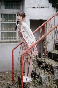 Portrait of young woman standing by railing