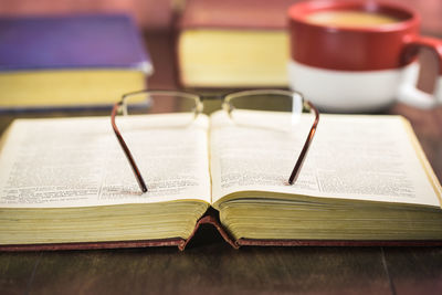 High angle view of books with eyeglasses and drink on table