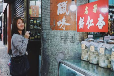 Woman standing by text on wall