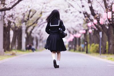 Rear view of woman walking on road