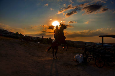 People on beach against sky during sunset